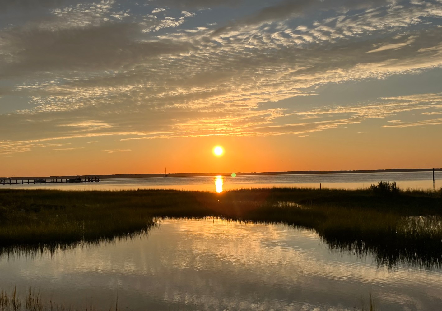 Sunset over the Chincoteague marshes with colorful clouds reflecting on calm coastal waters